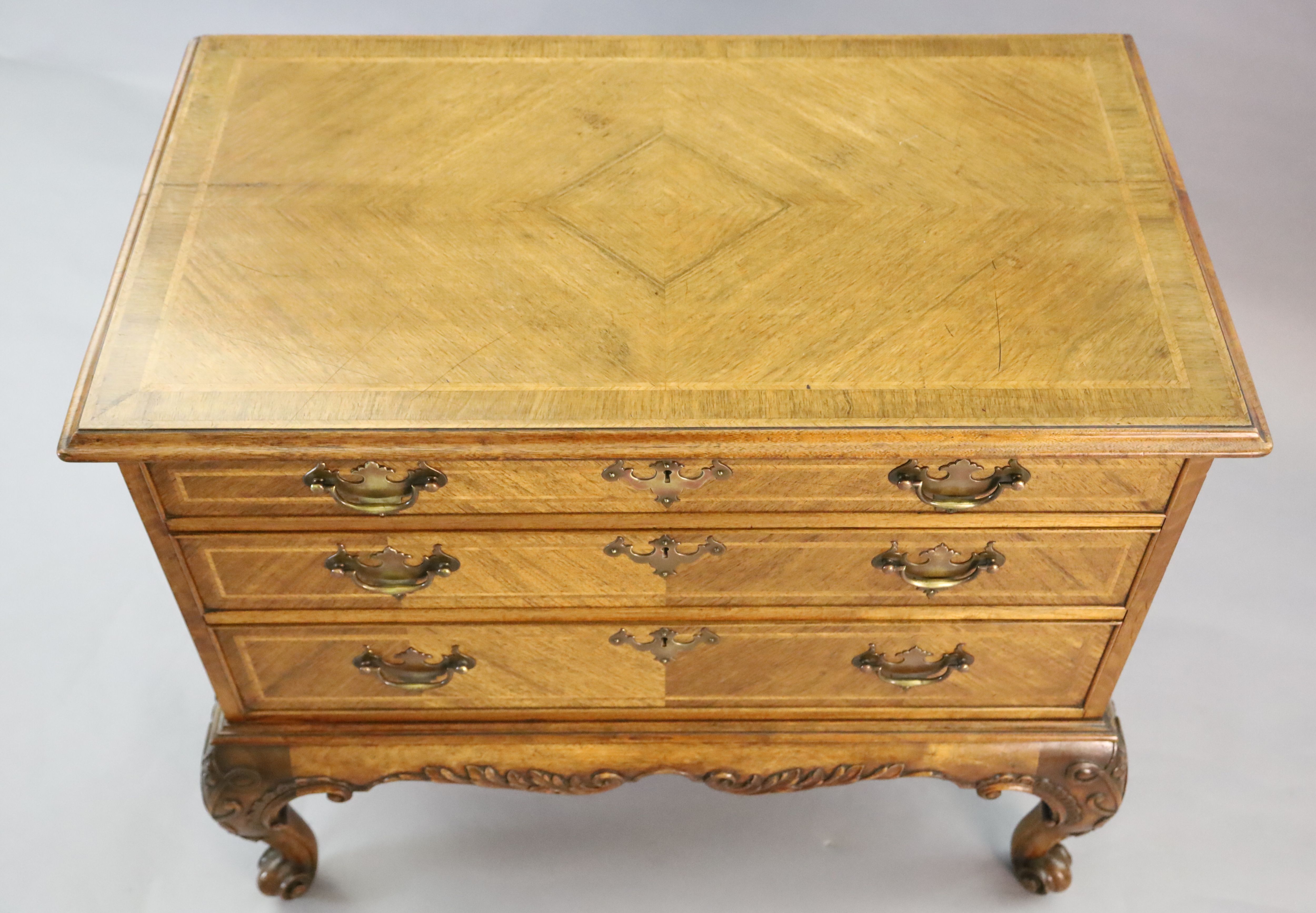 A Georgian style crossbanded walnut chest of three graduated long drawers, W.3ft 1in. D.1ft 10in. H.2ft 8in.
